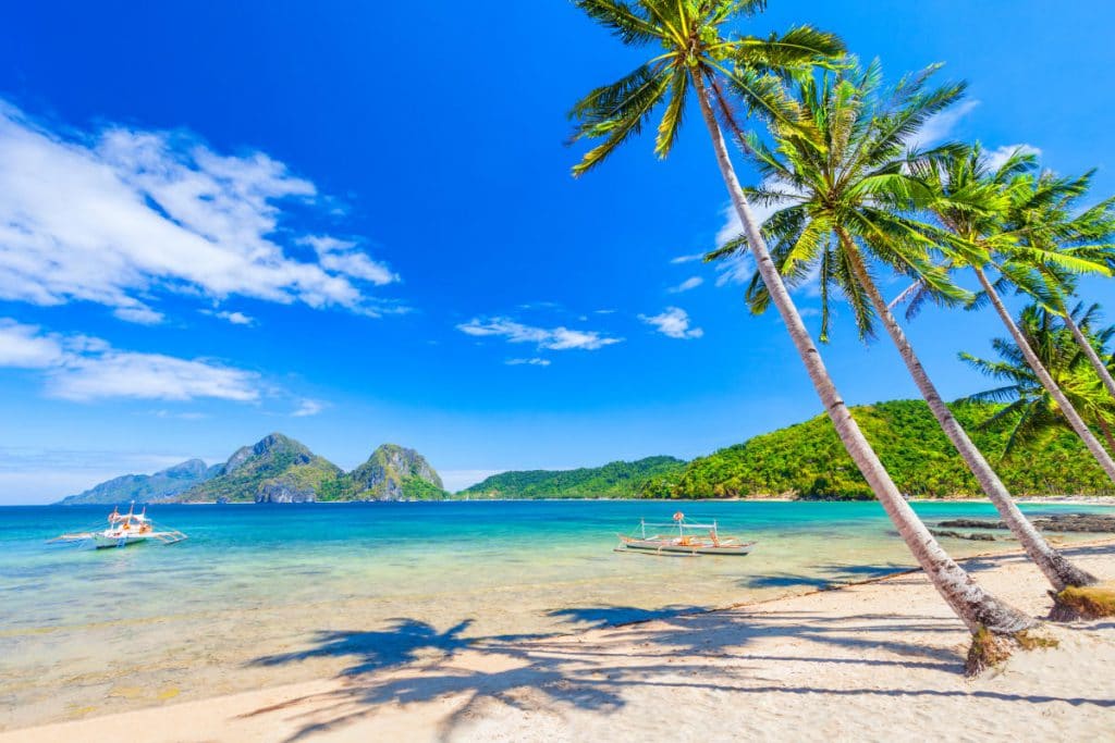 Strand met wit zand, kokospalmen en turkoois water in de provincie El Nido, het eiland Palawan in de Filippijnen