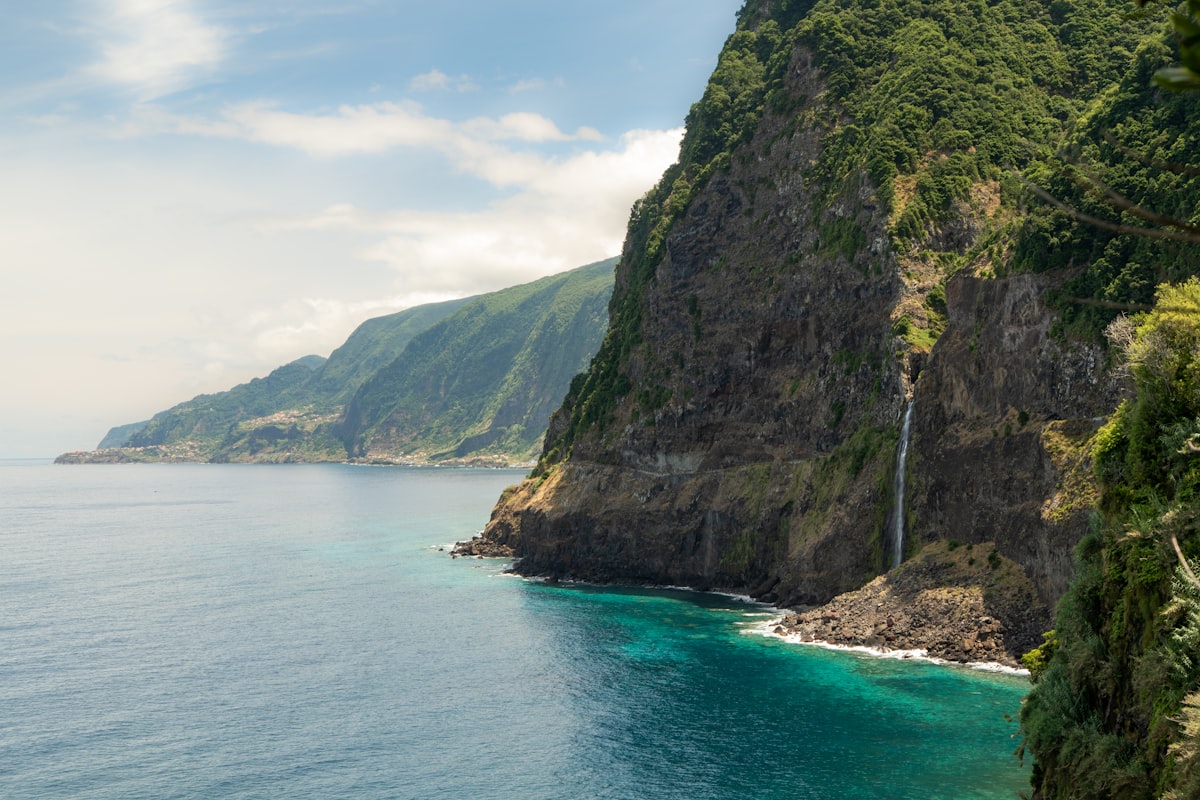 Coastal cliffs with a waterfall cascading into the ocean.
